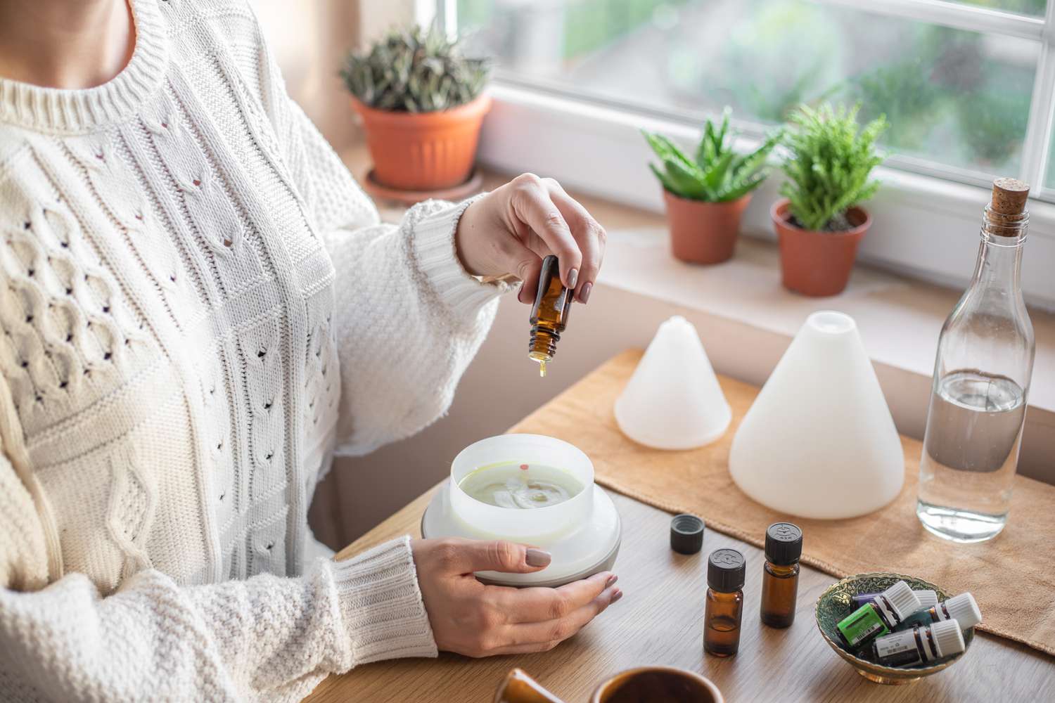 woman in sweater makes oil diffuser