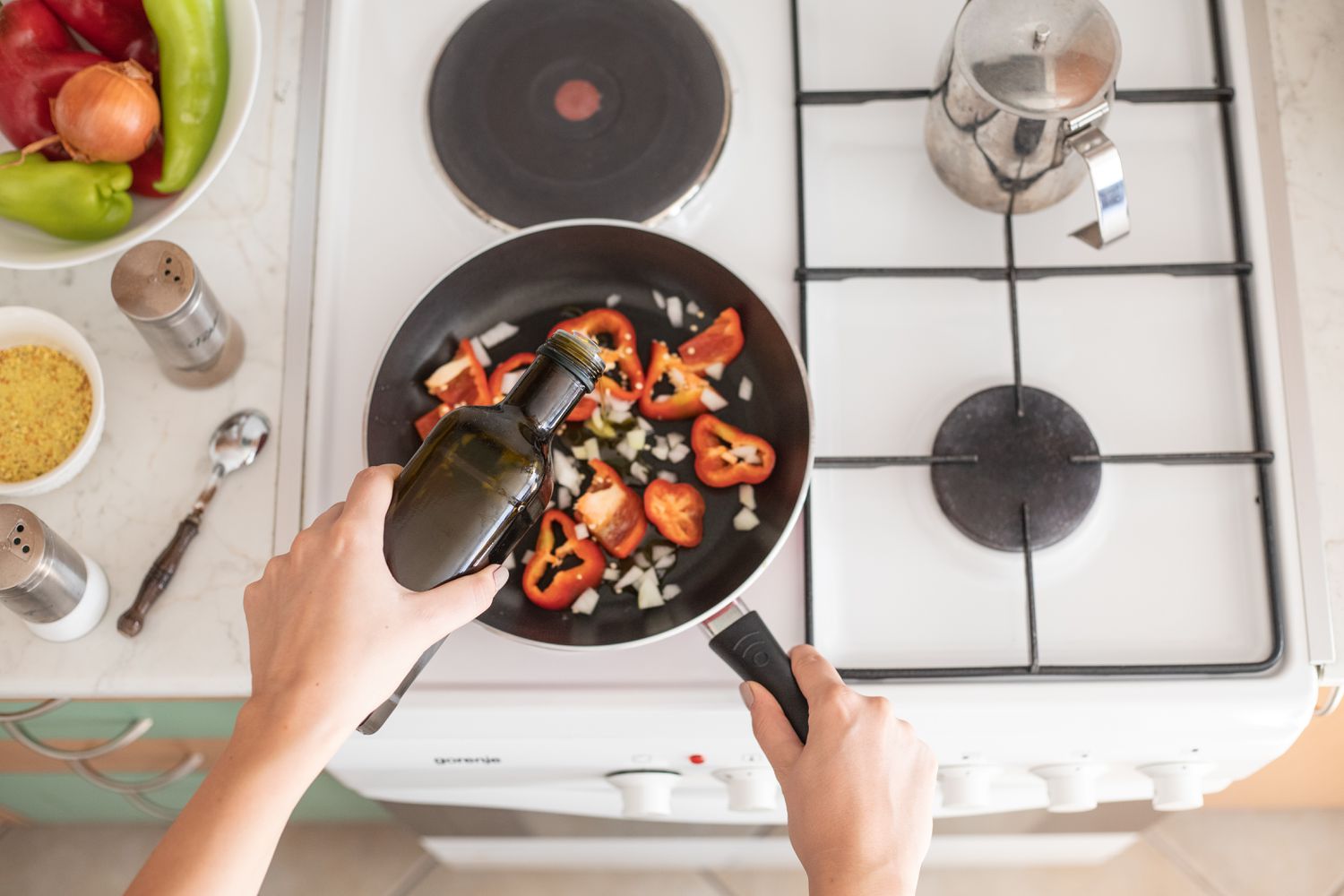 hand pours cooking oil into skillet