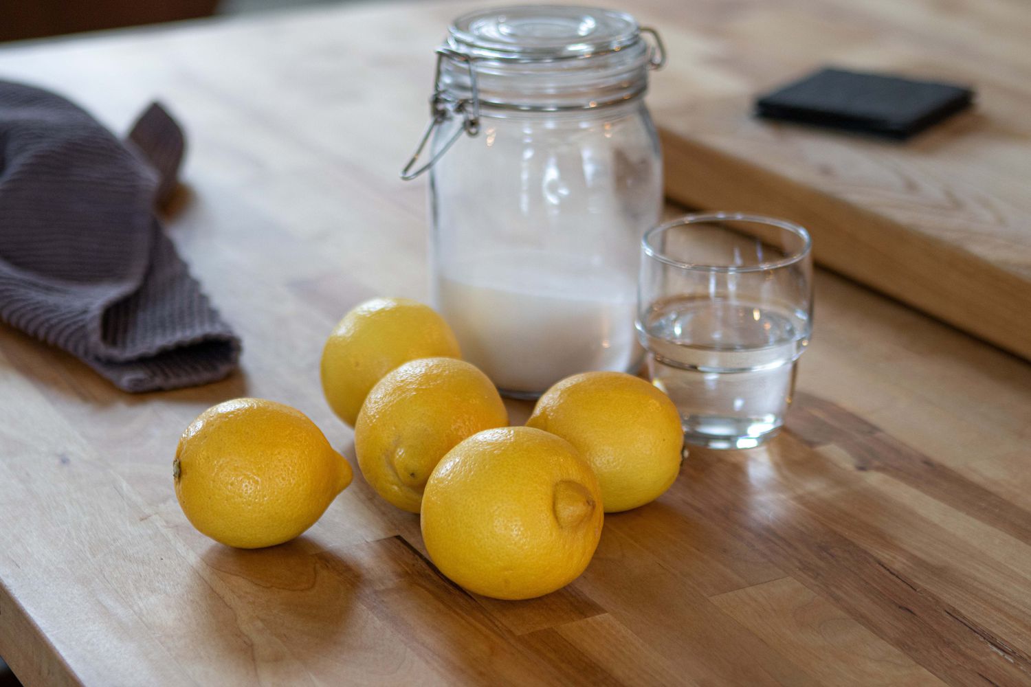 beauty shot of baking soda in glass canister with vinegar and several lemons