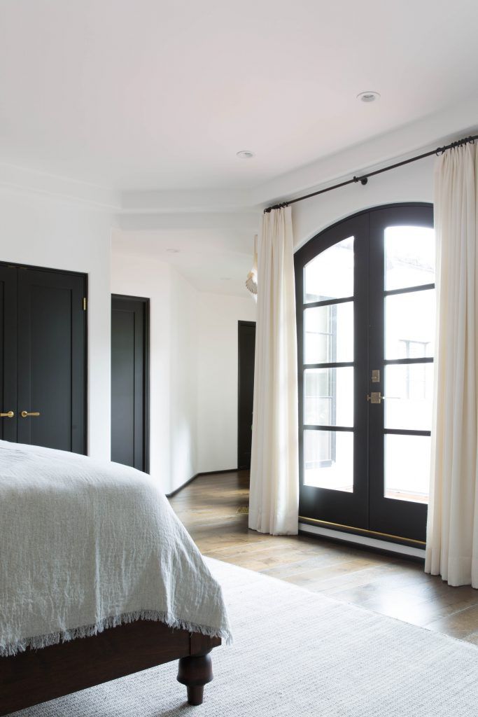 A bedroom with curtains hanging over glass doors