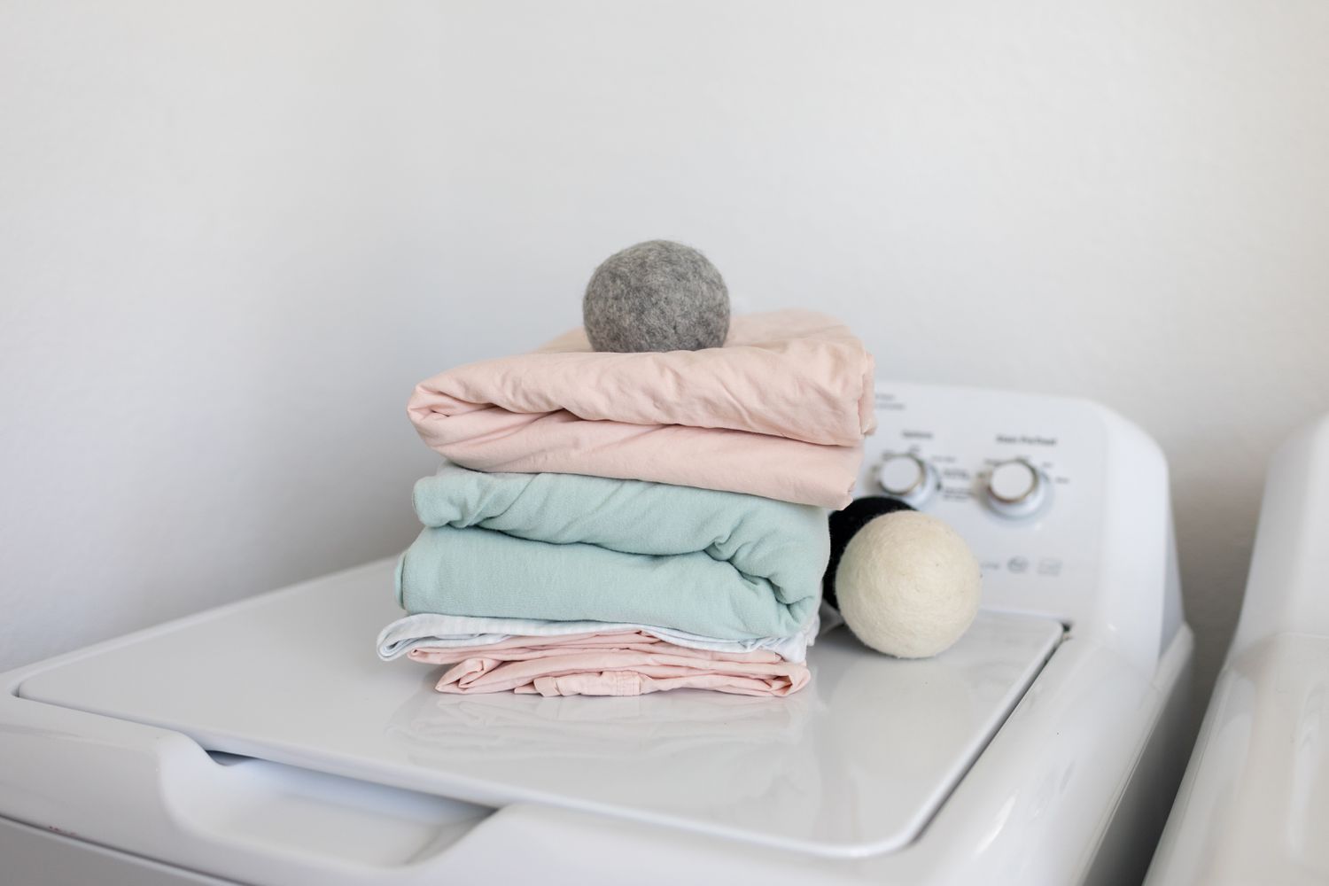 stack of folded bed sheets and wool dryer balls on top of washing machine