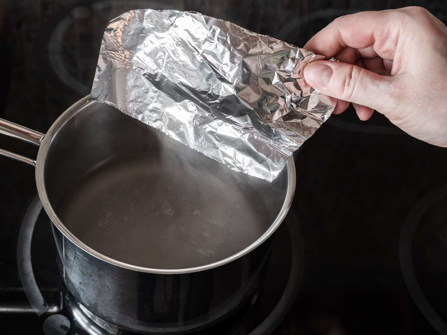 putting aluminum foil in pot with boiling water